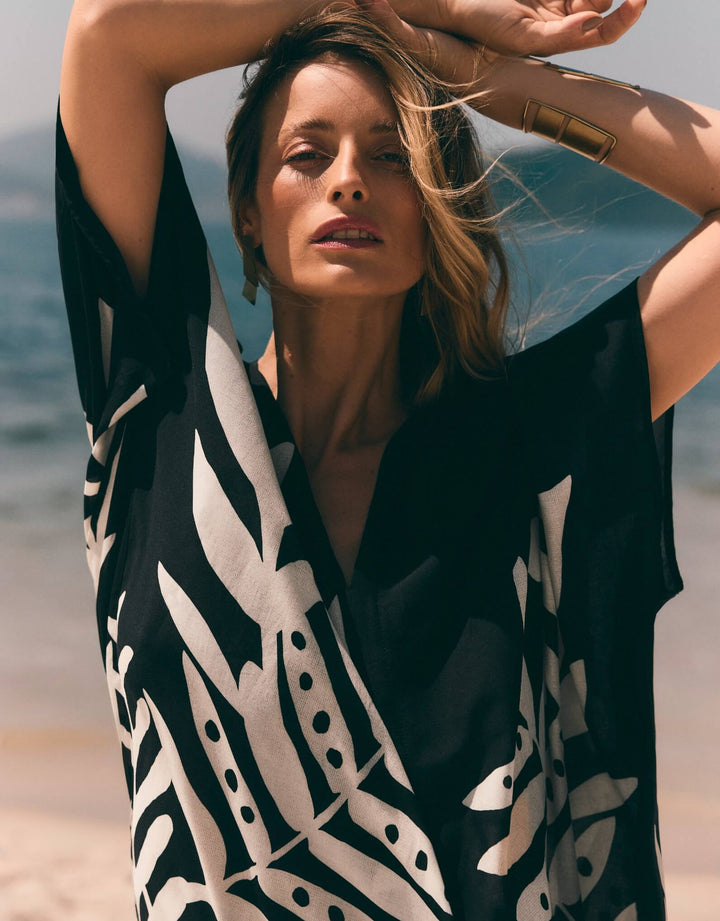 Lenny Niemeyer Frame Kaftan Dress in Jungle with tropical foliage print, V-neckline, loose sleeves, long length, styled over black swimwear.