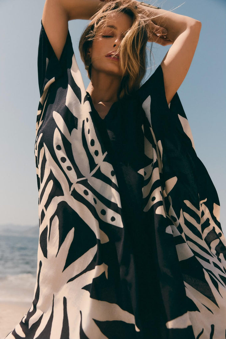 Lenny Niemeyer Frame Kaftan Dress in Jungle with tropical foliage print, V-neckline, loose sleeves, long length, styled over black swimwear.